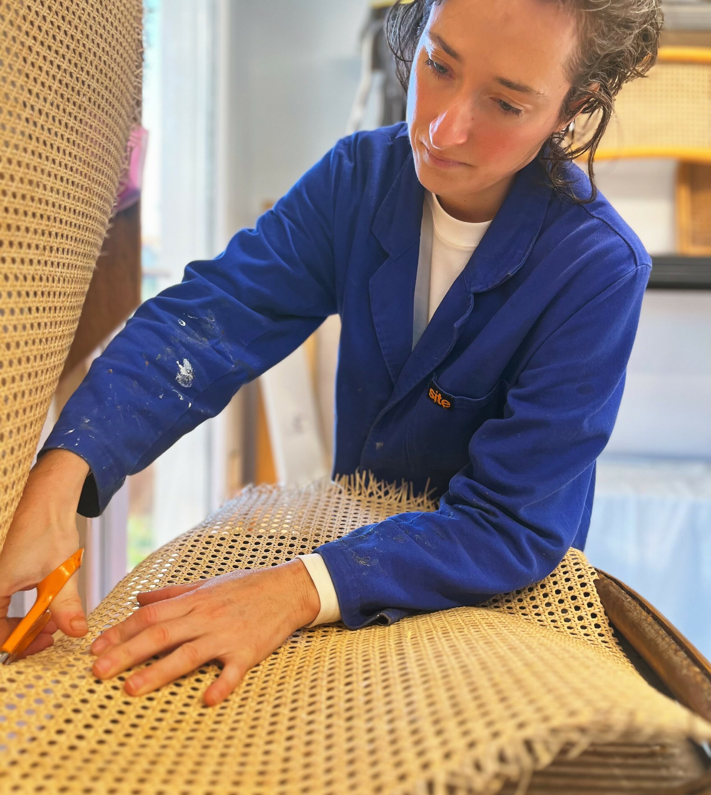 On voit l'artisan découper la toile de cannage